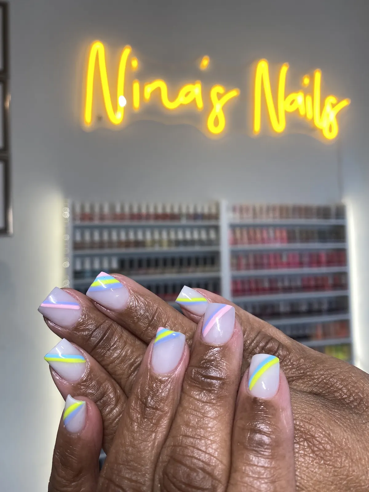 Nina's Nails neon sign above the polish wall at Simpson Road