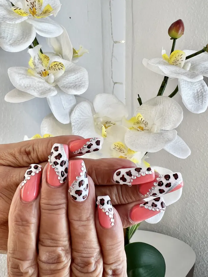 Coral and dalmatian-print nails beside orchids